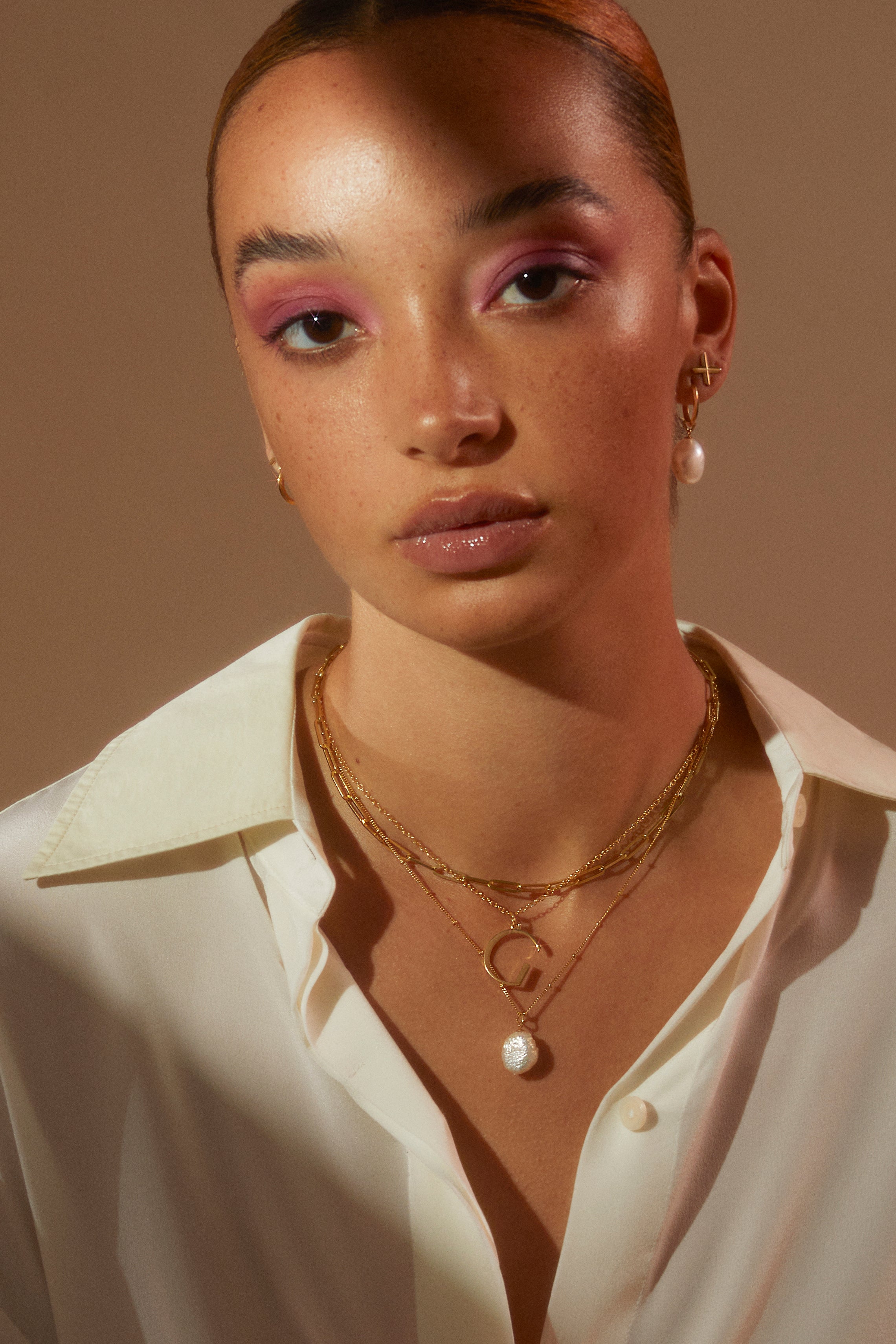 Model wearing layered necklaces featuring our G Anne Initial Necklace in a white shirt looking to camera