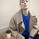 Model wearing blue jumper looking to camera wearing our Hedy Pearl Drops whilst enjoying a coffee