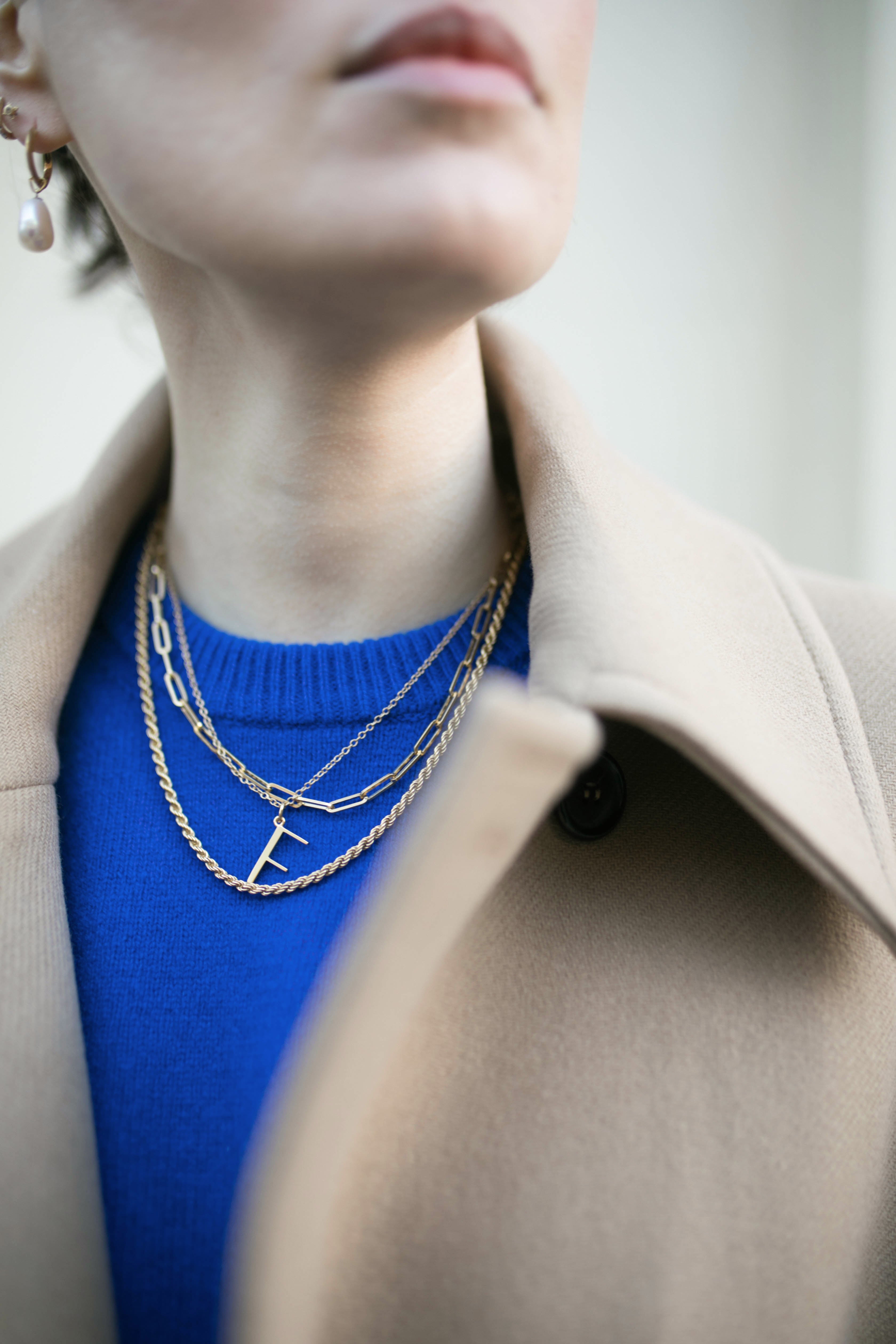 Close up of model wearing F necklace and several Antonia Guise chains. 