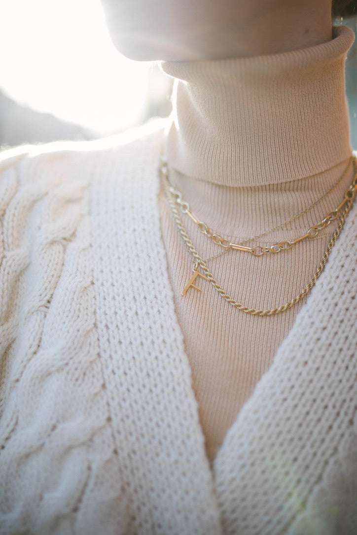 Model wearing chunky white knit cardi and F Anne Initial Necklace with Rosalind chain and Mary Figaro chain