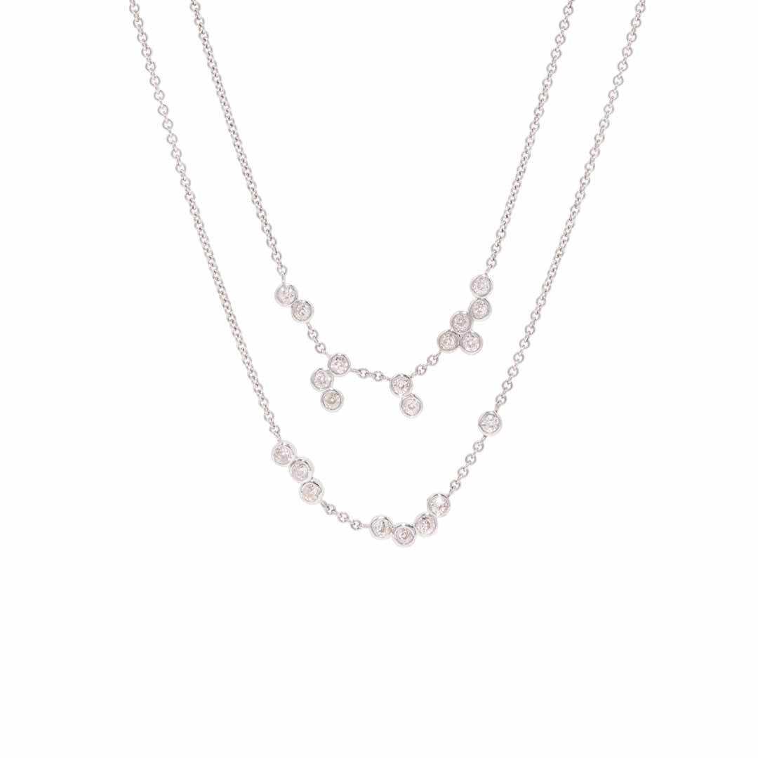A pair of diamond bezel set necklaces on a fine chain hanging from the top of the image. One a white background.
