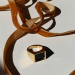 Eve Ring on a white background with shadows and mustard velvet ribbon snaking around it
