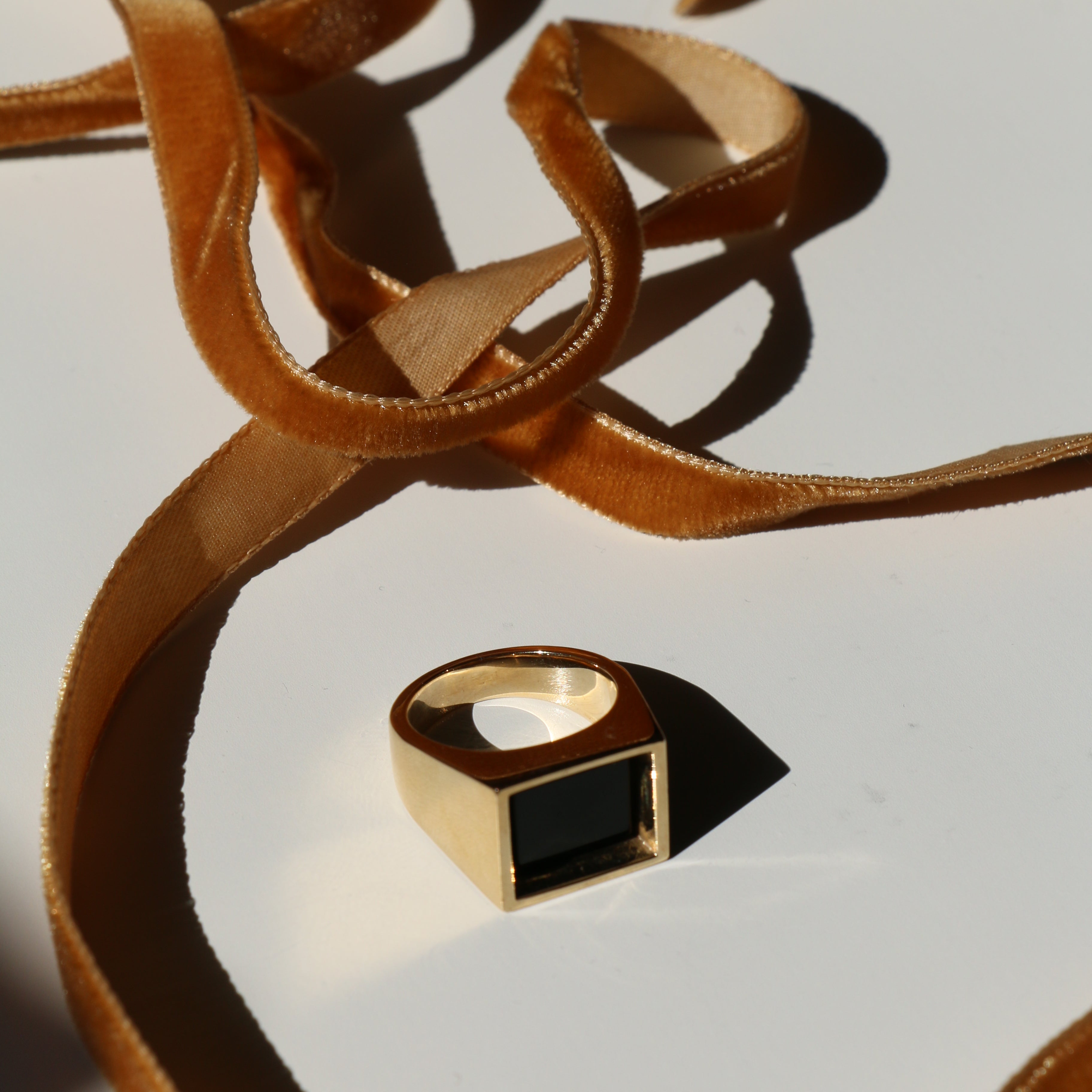 Eve Ring on a white background with shadows and mustard velvet ribbon snaking around it