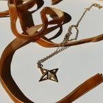 Theodora Gold Necklace on a white background with shadows and mustard velvet ribbon snaking around it