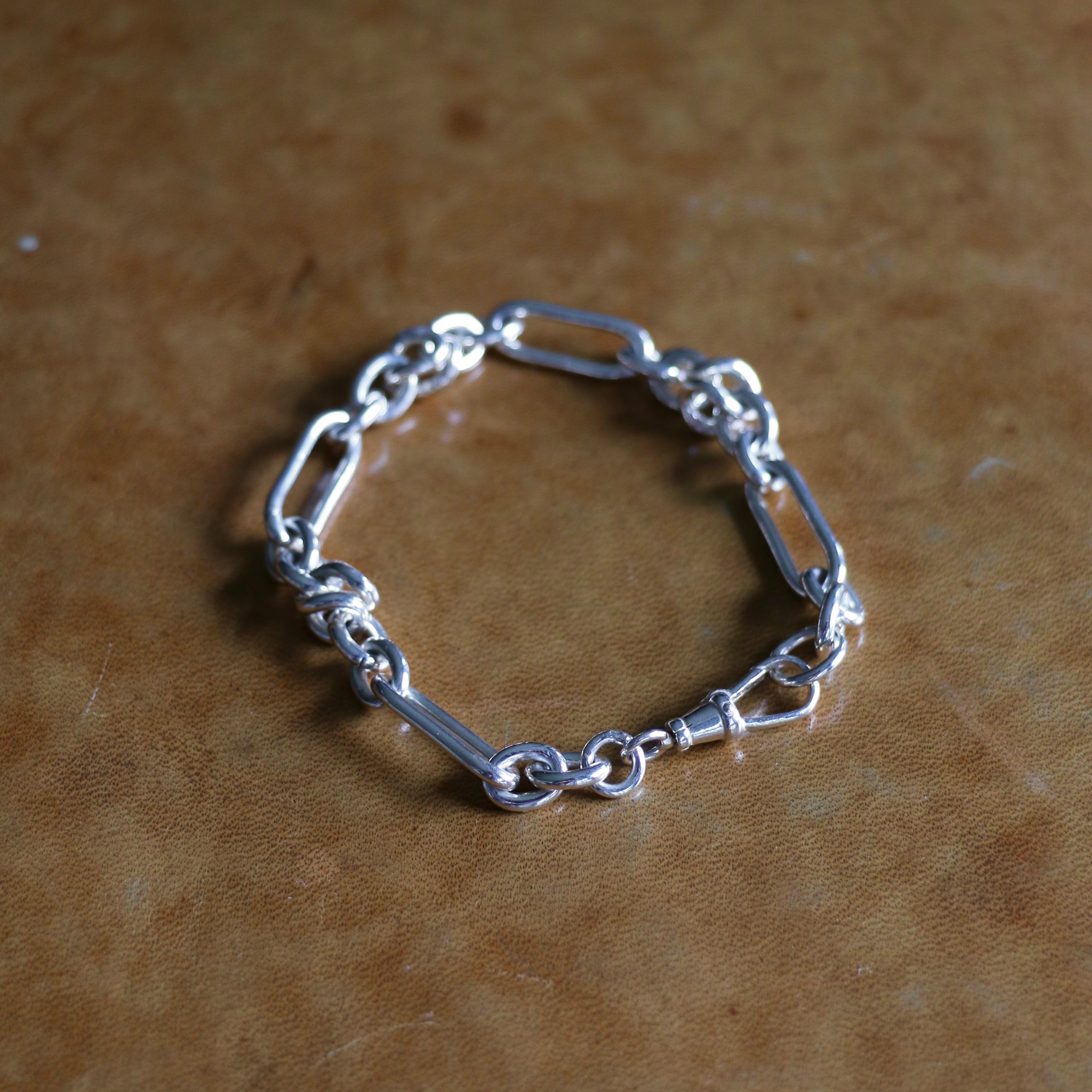 Silver Artemisia bracelet stretched out on a leather background