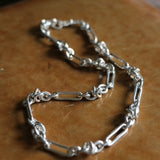 Silver Artemisia Necklace stretched out on a leather bench