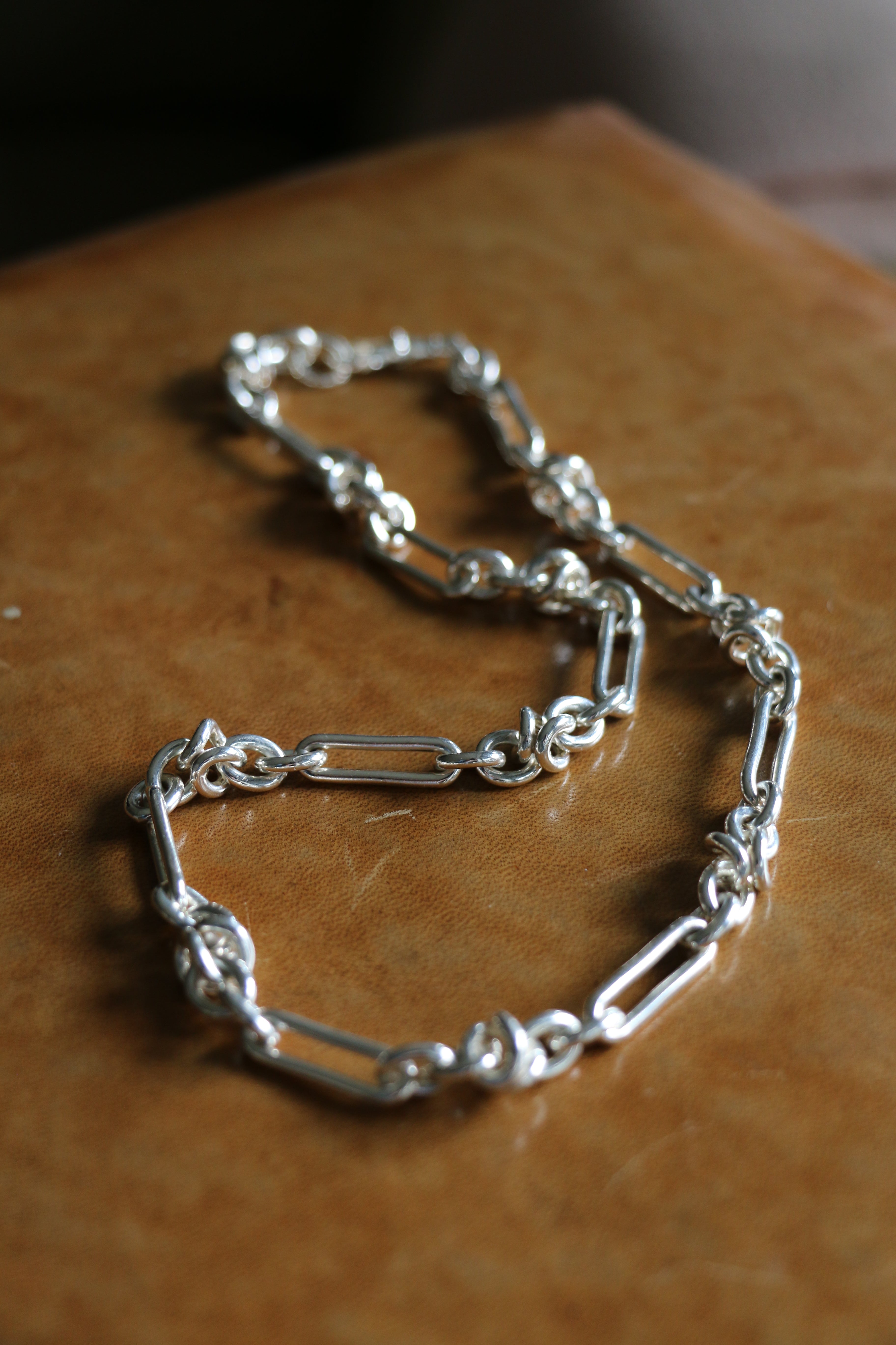 Silver Artemisia Necklace stretched out on a leather bench