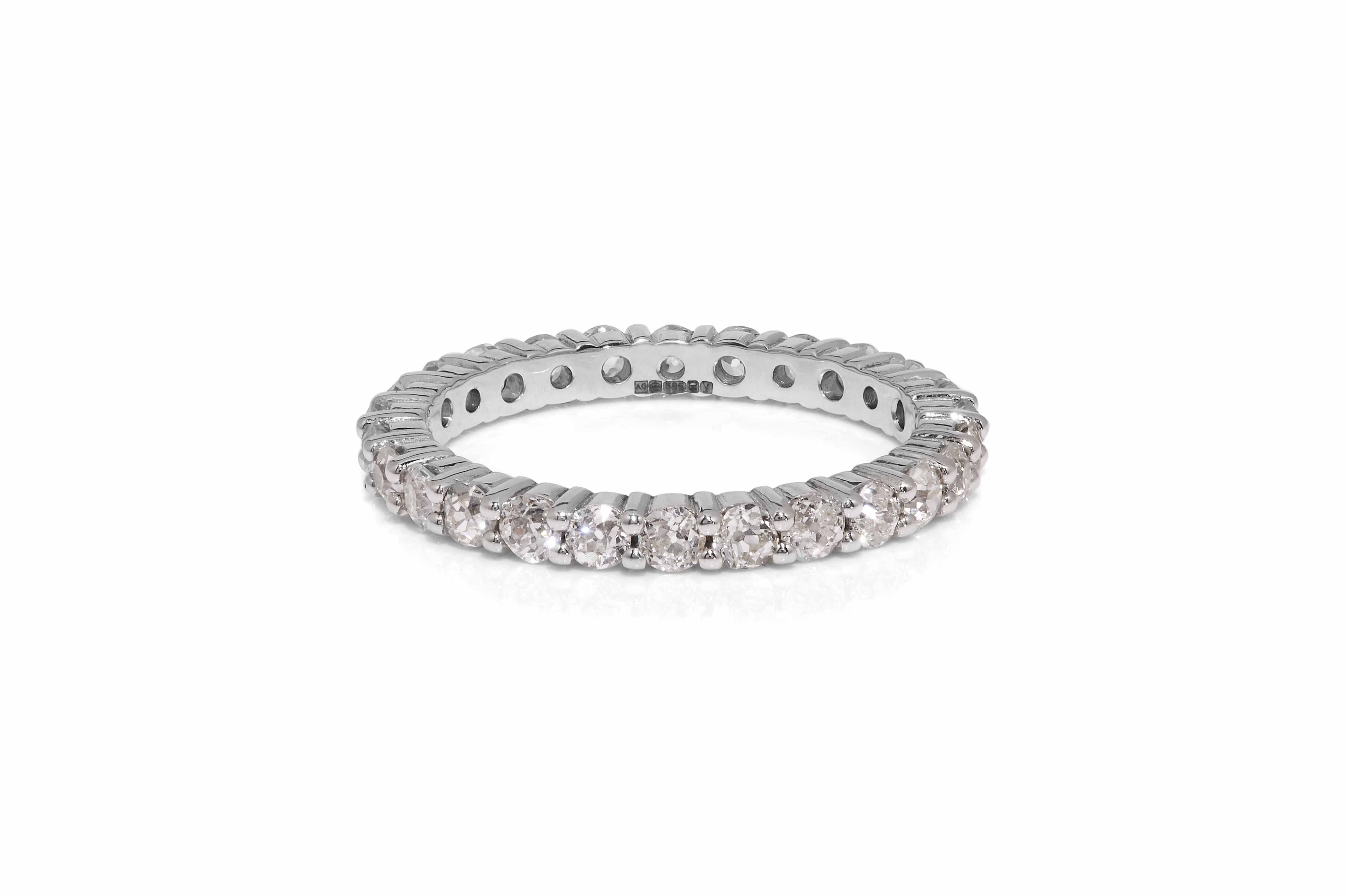 A reused, claw set, diamond eternity ring set in 14ct white gold lying on white background with shadow