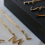 An assortment of initial necklaces laid out on a black background