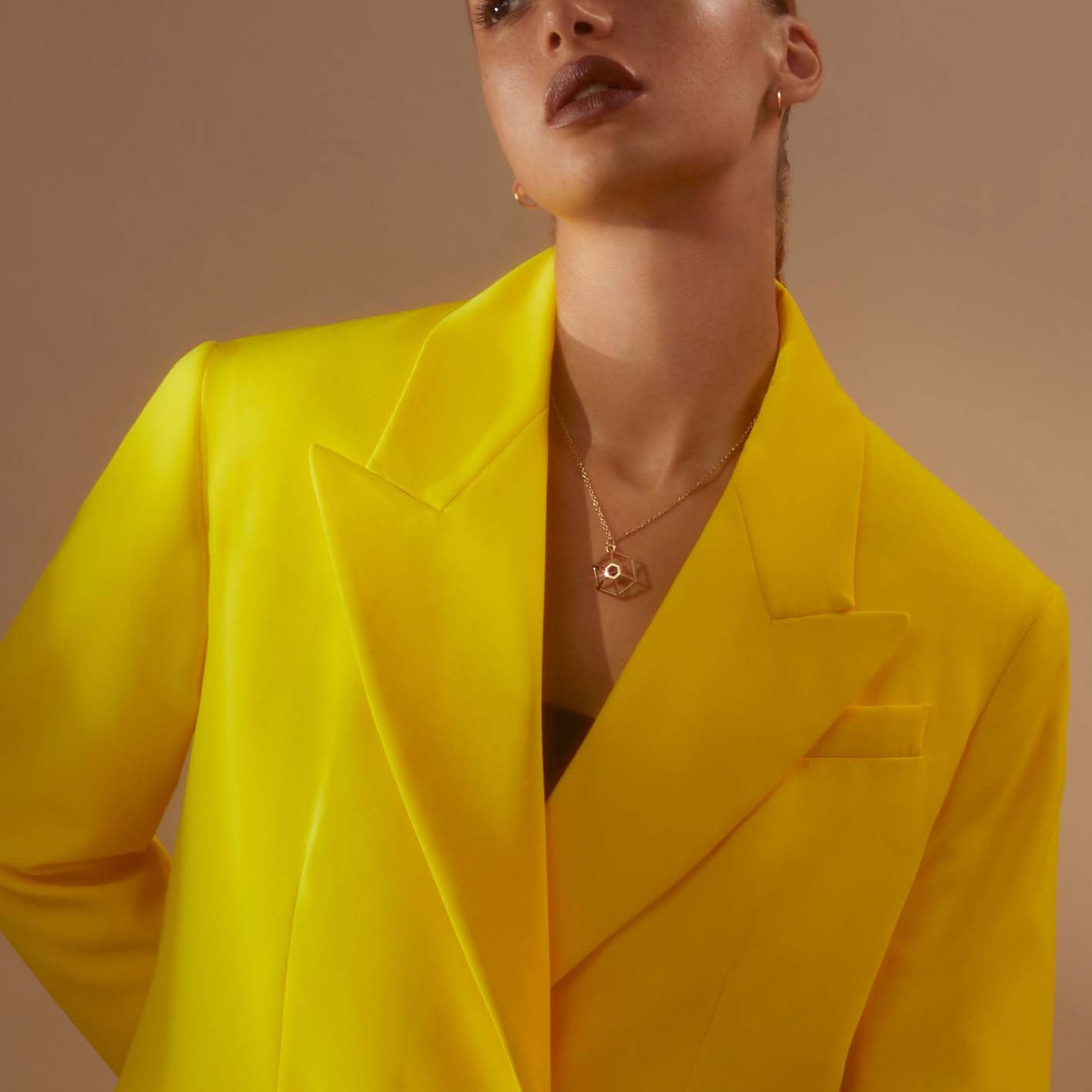 Model wearing yellow jacket and Circe Hexagon Necklace