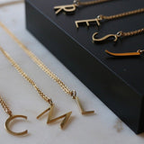 An assortment of initial necklaces laid out on a black background