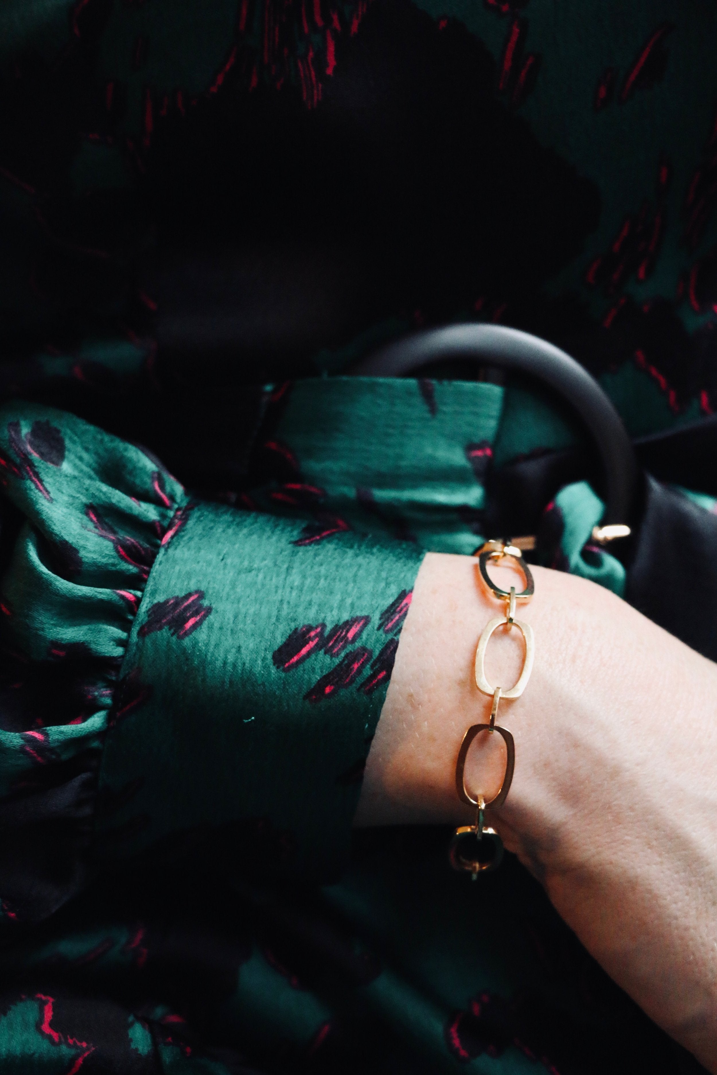 Close up of model wearing green silk dress with cuff detailing and our Nancy gold vermeil chain bracelet