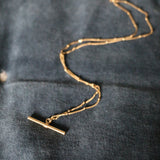 Our handmade in England, Gold Vermeil T-Bar Necklace lying on a blue velvet background