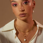 Model wearing layered necklaces featuring our G Anne Initial Necklace in a white shirt looking to camera