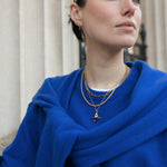 Close up of model in front of fluted columns wearing an assortment of Antonia Guise Gold Vermeil Jewellery
