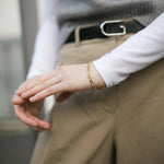 A close up shot of our Mary Figaro Bracelet worn by a model wearing camel trousers