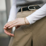 A close up shot of our Mary Figaro Bracelet worn by a model wearing camel trousers