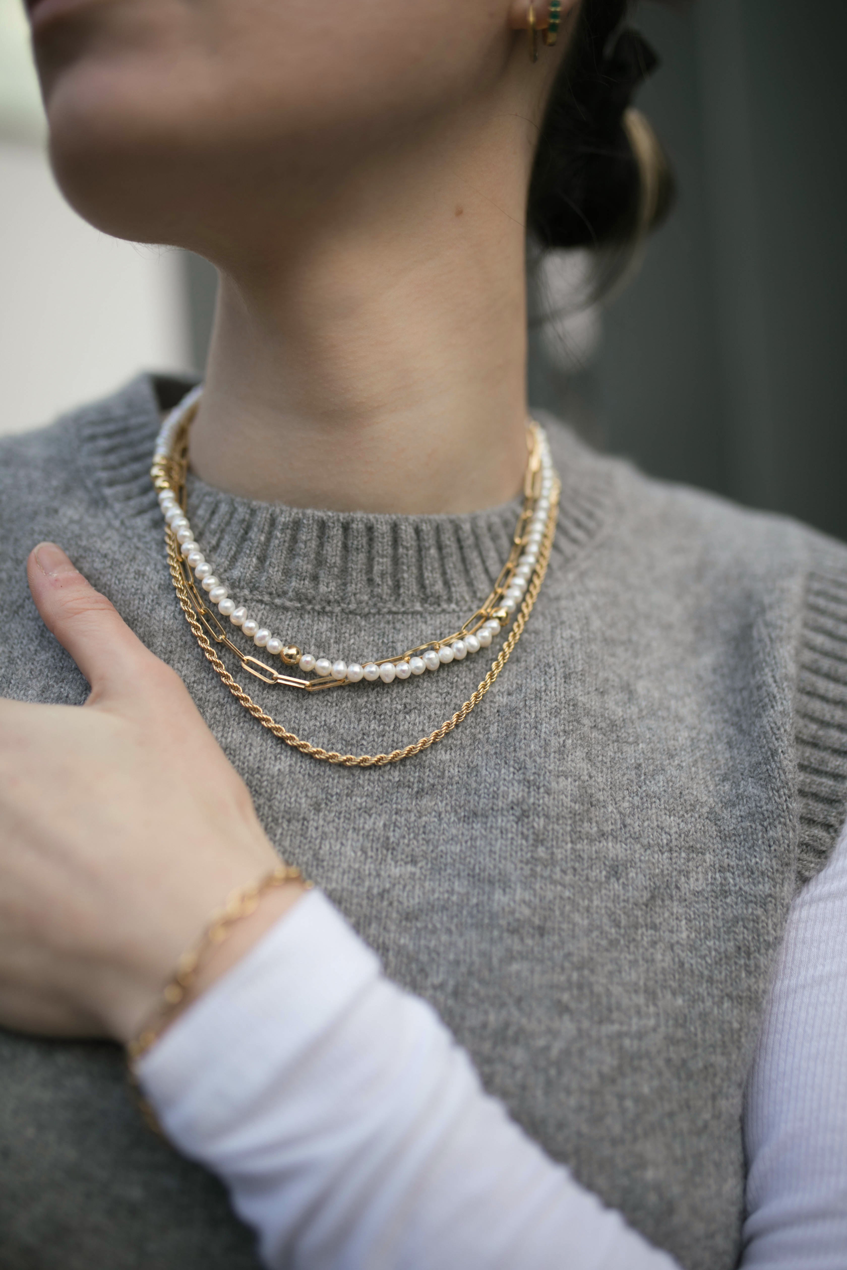Model wearing grey sleeveless jumper and stack of Antonia Guise chains with our Grace Pearl Necklace