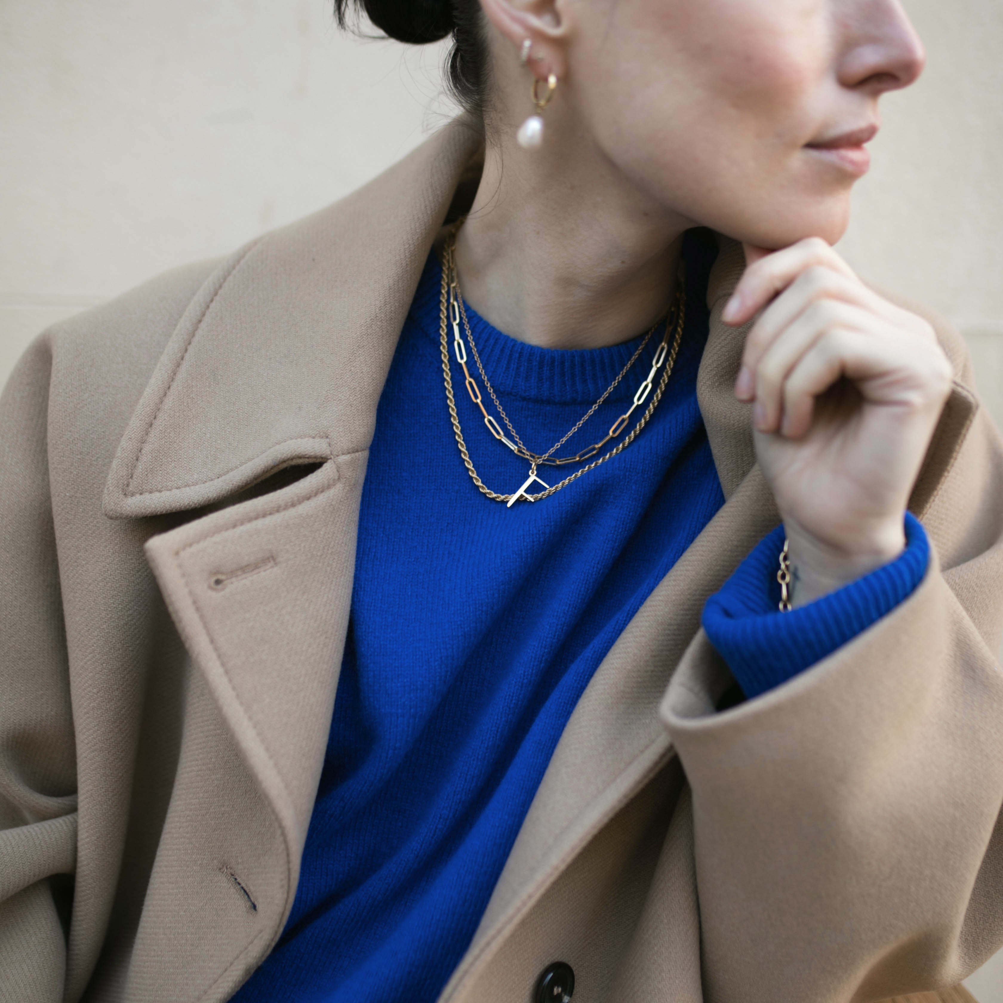 Model wearing F Anne Initial Necklace and several other Antonia Guise chains looking pensively to the right