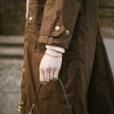 Model wearing brown wax jacket with green handbag and our gold chain Mary Bracelet 
