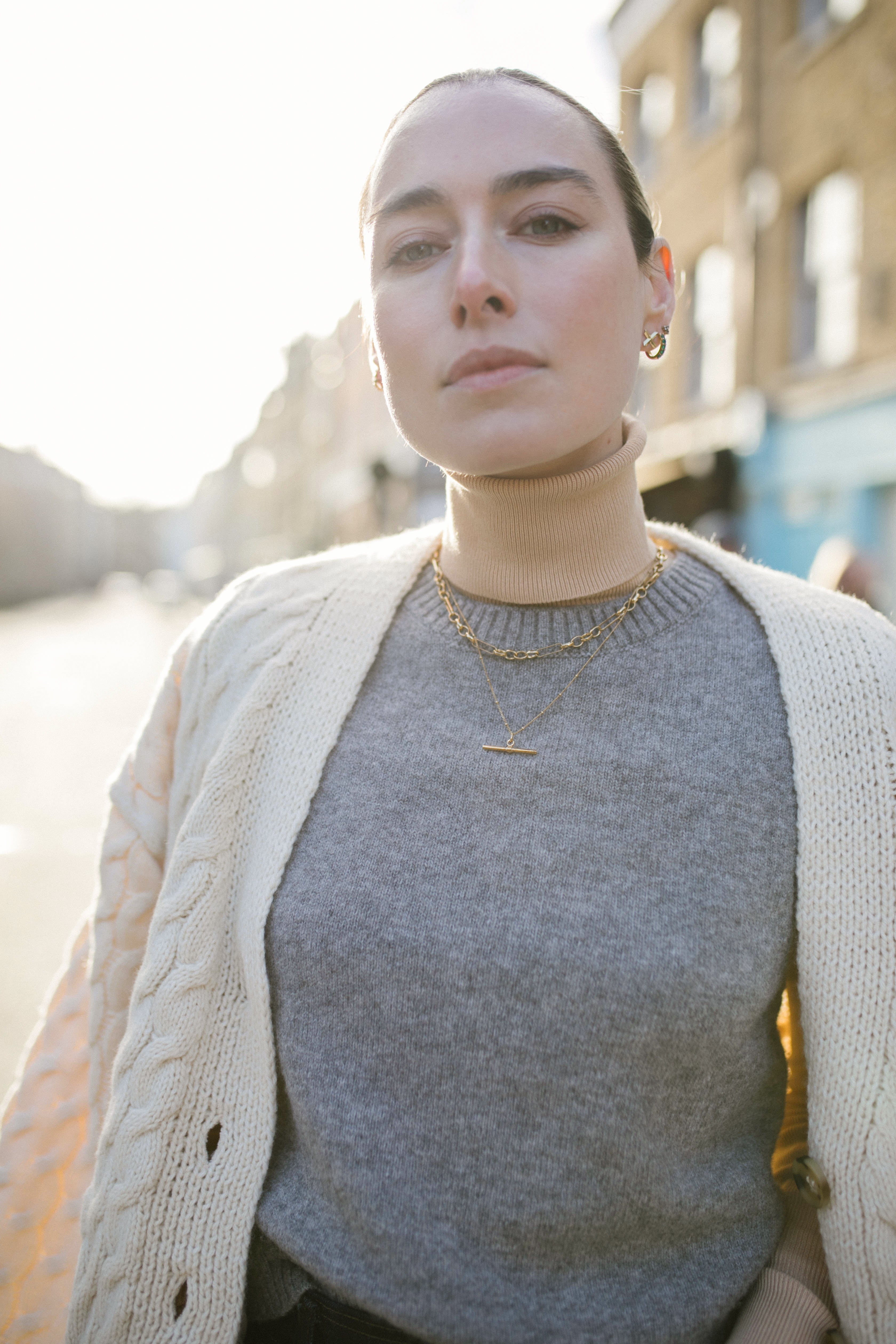 Model looking to camera wearing a white knit cardigan and our Mary Figaro 16 inch chain and Marlene T-Bar Necklace
