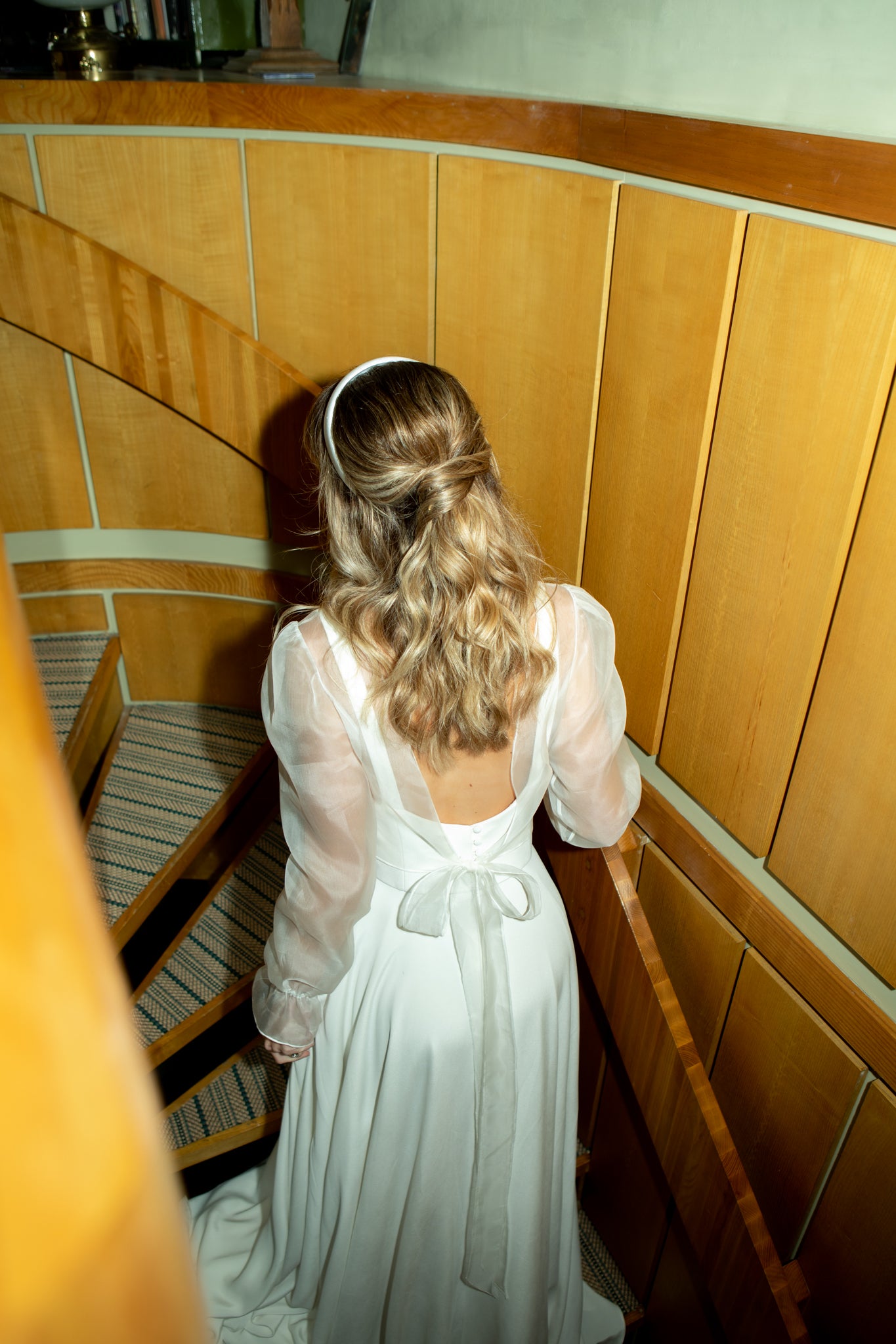 Bride walking up stairs in Andrea Hawkes wedding dress with ring from bespoke engagement ring designer Antonia Guise