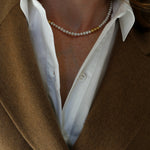 Close up of Grace Pearl Necklace on model wearing white shirt and camel wool coat