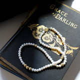 Grace Pearl Necklace lying on a book a out our muse Grace Darling