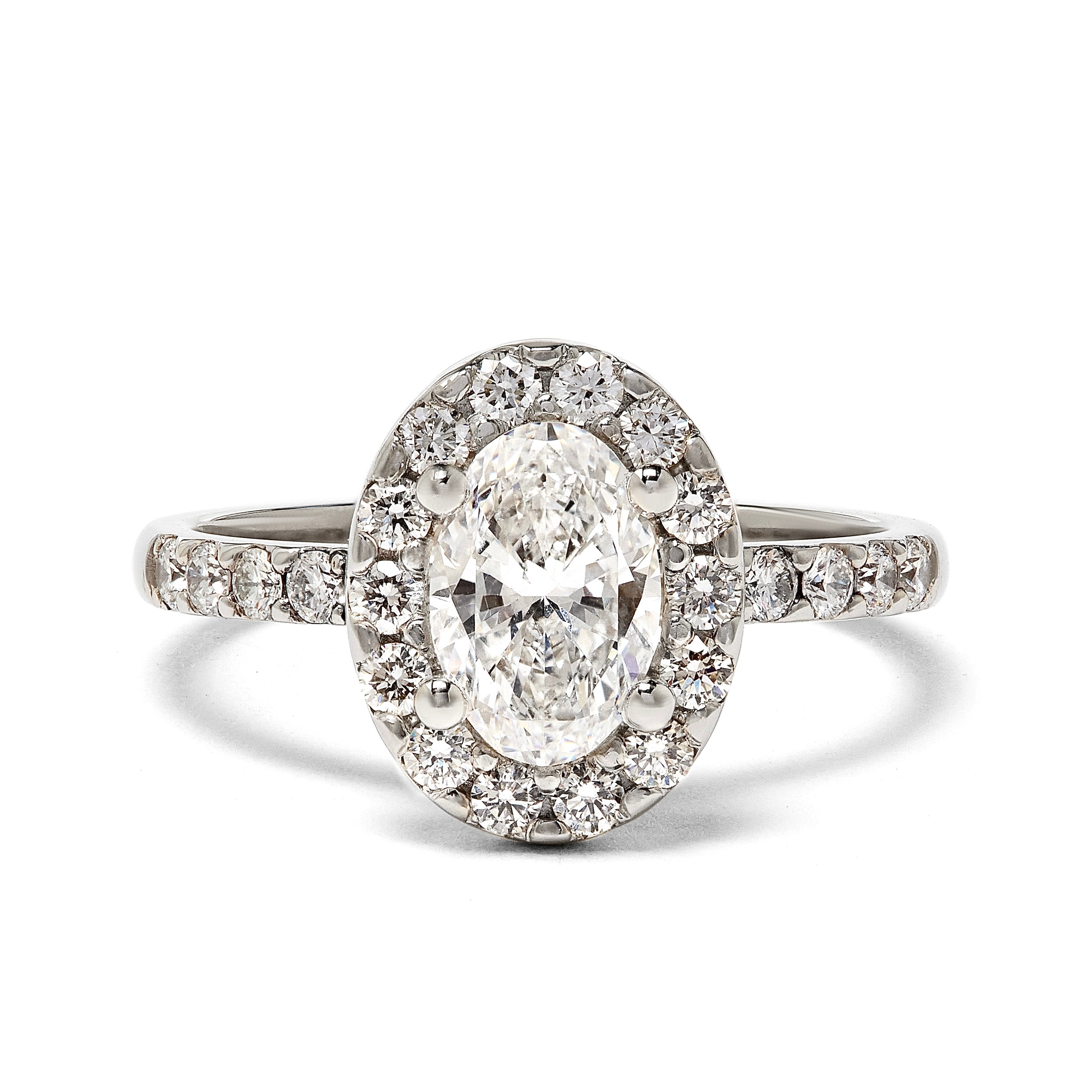 A unique, bespoke diamond engagement ring. An oval diamond set with a diamond  halo and pave band. All set in recycled platinum. Designed by London based engagement ring designer Antonia Guise.