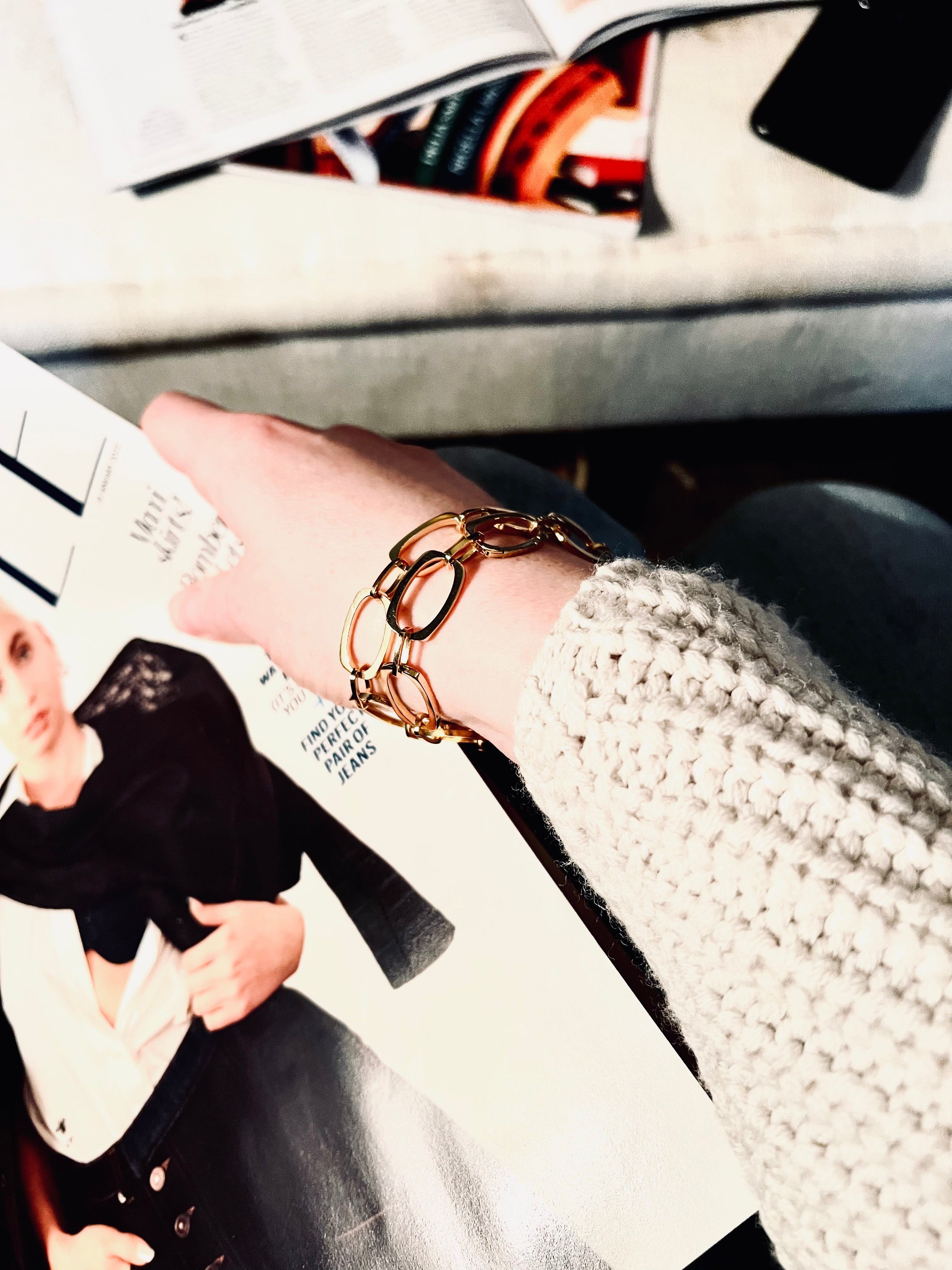 High flash image of model wearing knit jumper holding ELLE Magazine and wearing two of our Nancy Chain Bracelets