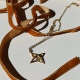 Theodora Gold Necklace on a white background with shadows and mustard velvet ribbon snaking around it