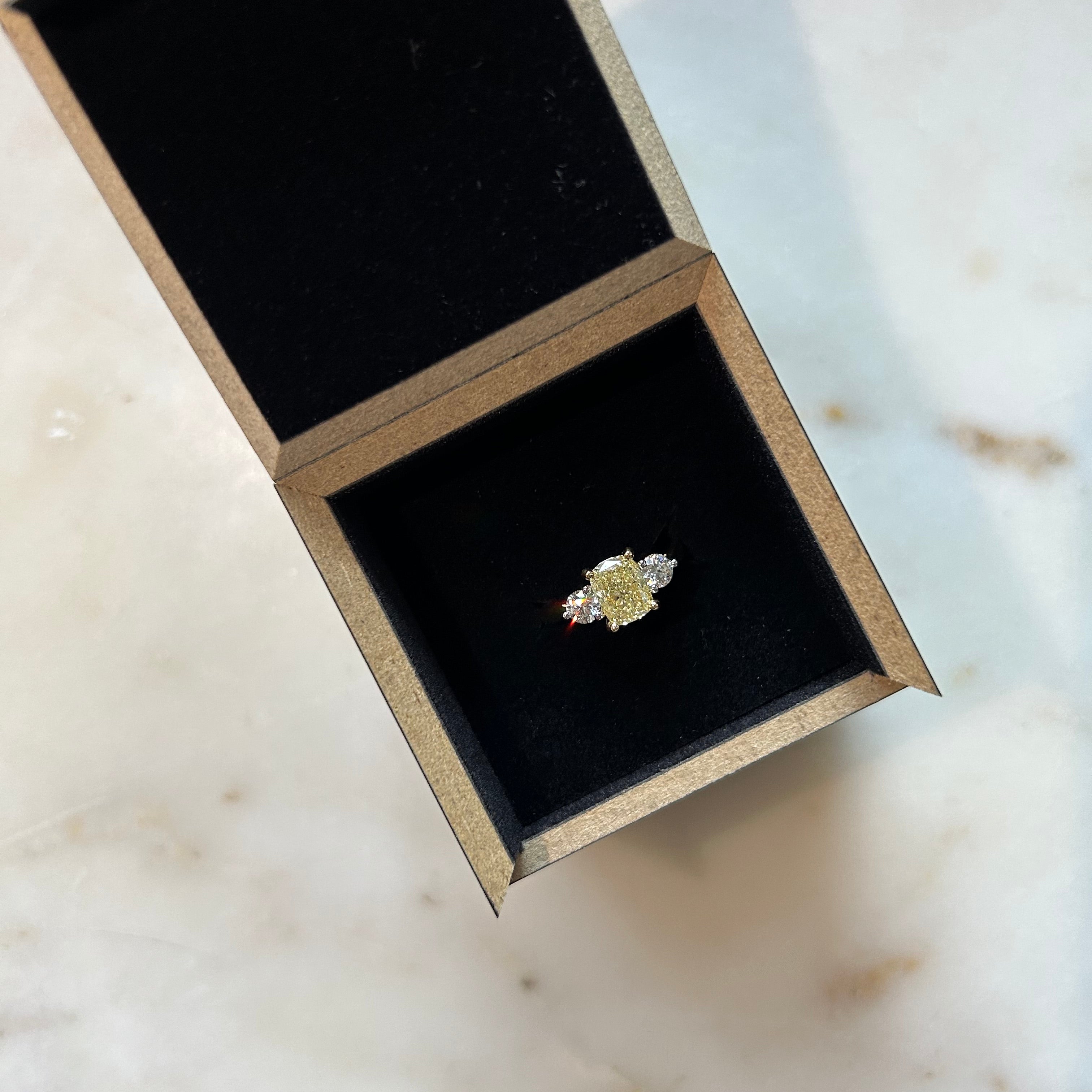 A Yellow diamond flanked by normal diamond trilogy ring in 18ct yellow gold in it's black presentation box