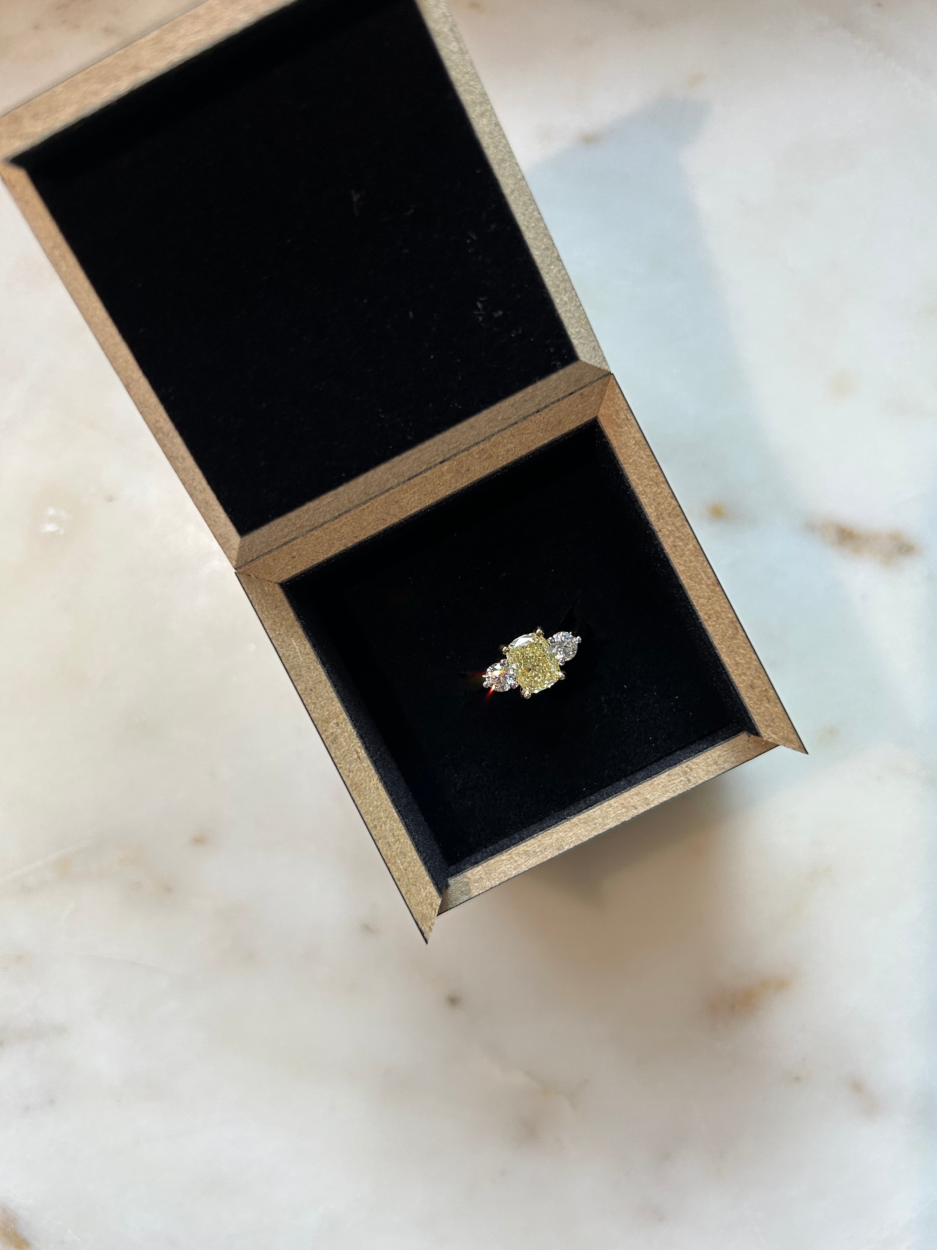 A Yellow diamond flanked by normal diamond trilogy ring in 18ct yellow gold in it's black presentation box