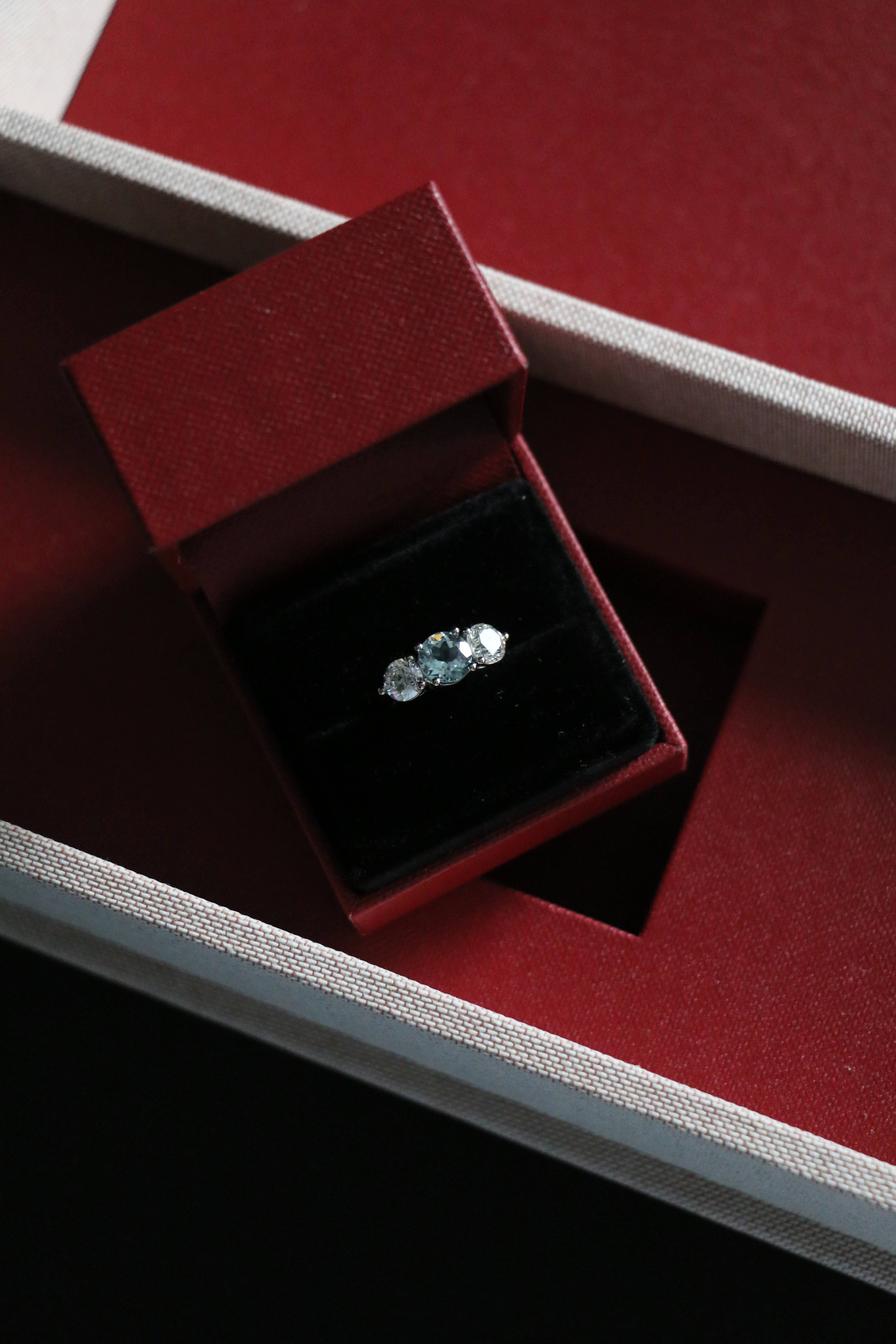 An aquamarine and diamond trilogy ring in it's presentation box. All designed by London engagement ring designer; Antonia Guise