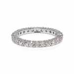 A shared claw 14ct round diamond eternity band lying on white background