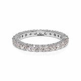 A shared claw 14ct round diamond eternity band lying on white background