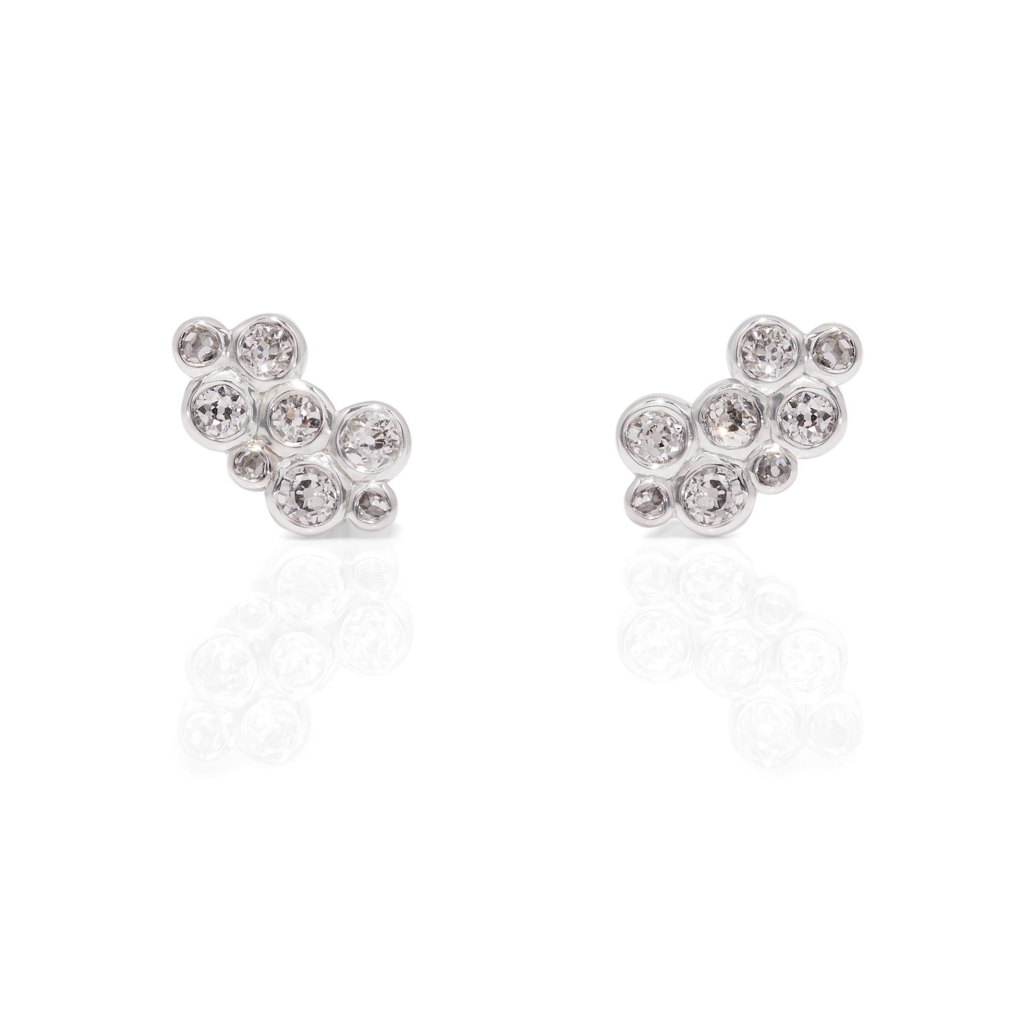 Pair of bezel set round diamonds clustered into wing shaped earrings on a white backgorund