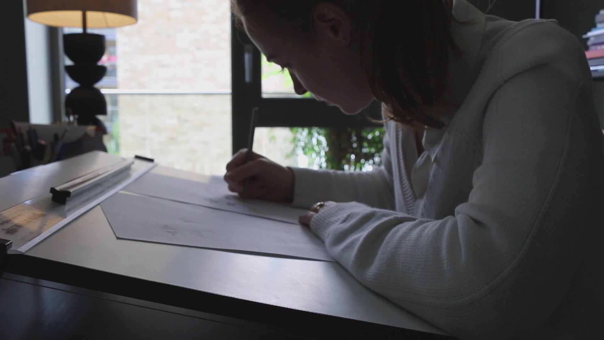 London based Engagement Ring jeweller Antonia Guise sitting at her desk in her studio designing a unique diamond engagement ring.