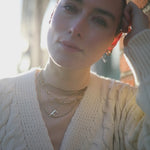 Backlit video of model wearing white chunky knit cardi and F anne initial with layered Antonia Guise Chains