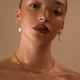 Model wearing our Gold Cecilia Huggie Hoops with our Pearl Drops looking to camera