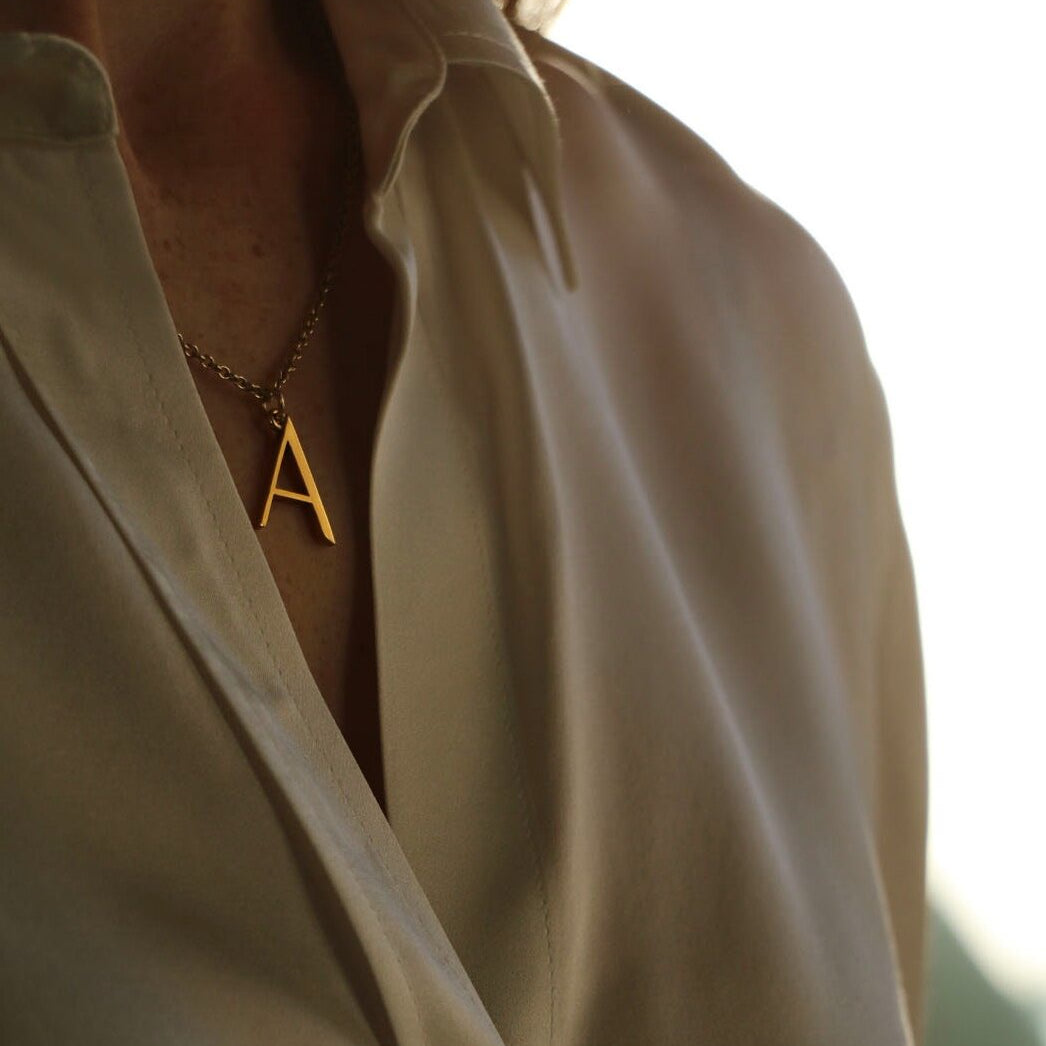 A initial necklace on model with white shirt
