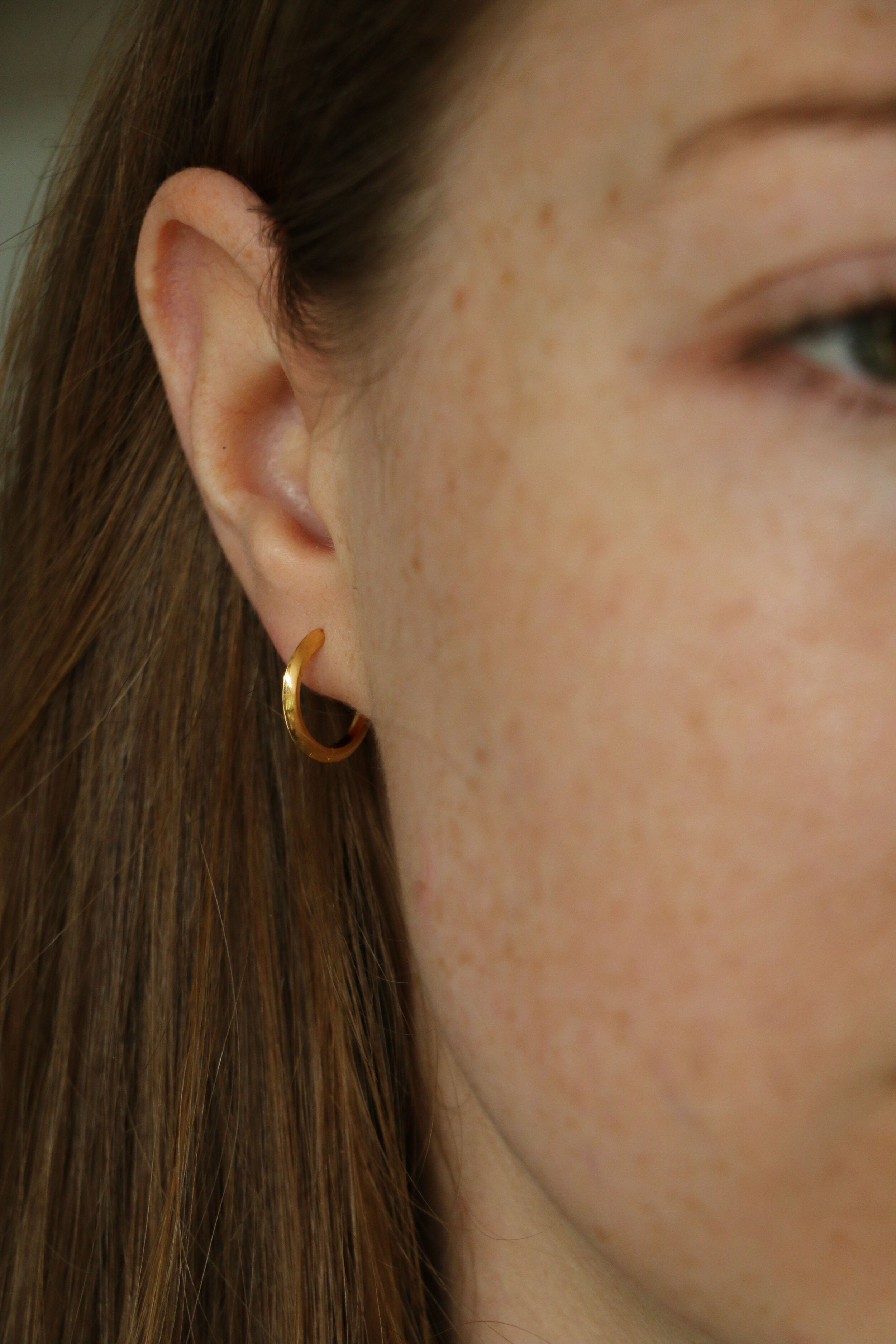 Close up shot of model wearing our Cecilia Gold Huggie Hoops