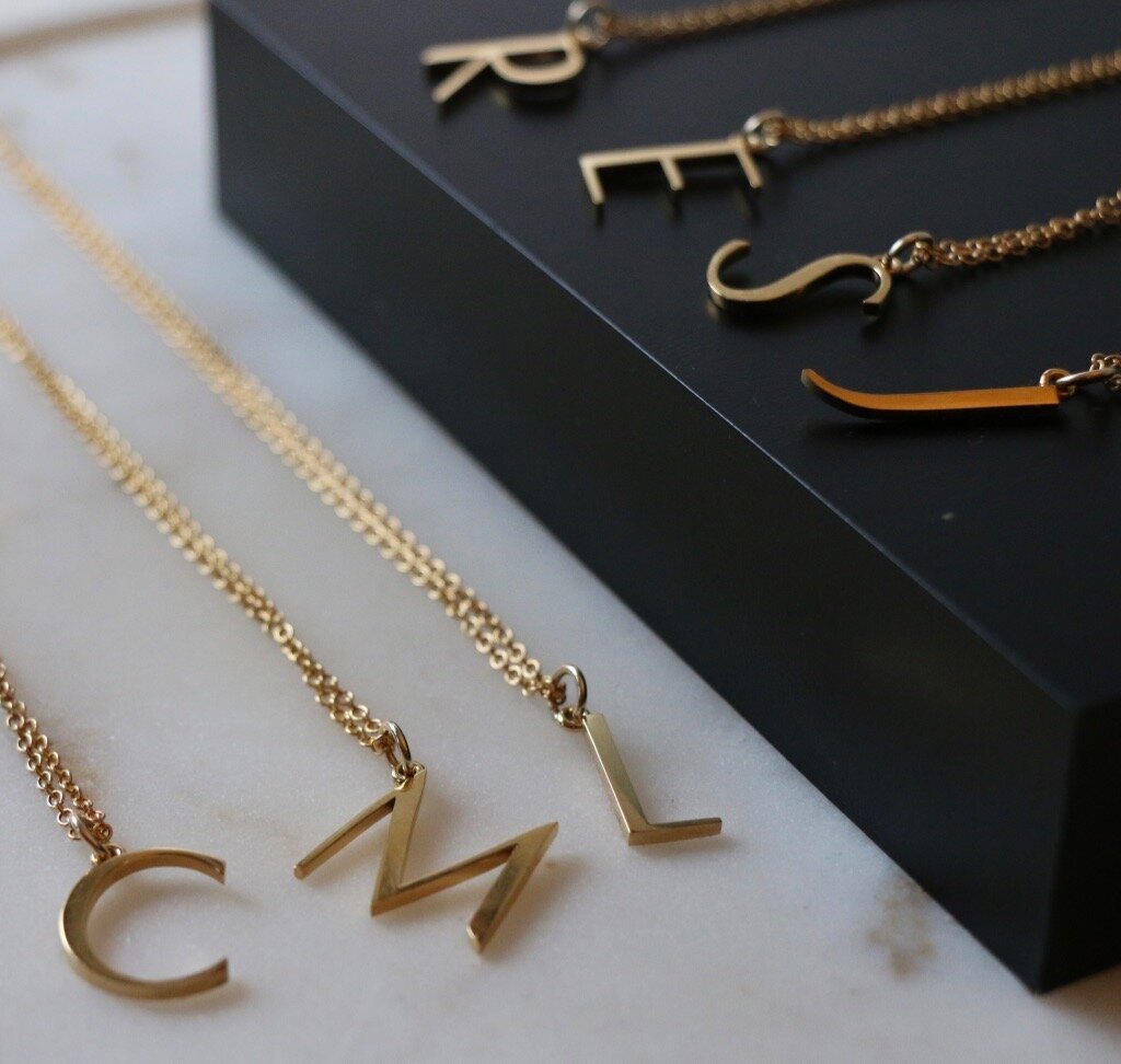 An assortment of initial necklaces laid out on a black background