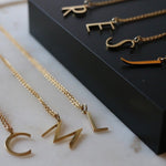 An assortment of initial necklaces laid out on a black background