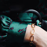 Close up of model wearing green silk dress with cuff detailing and our Nancy gold vermeil chain bracelet