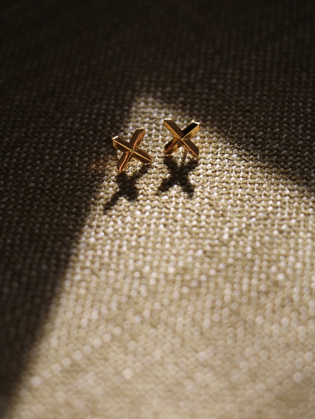 Gold vermeil Lily Cross Studs on green textured fabric